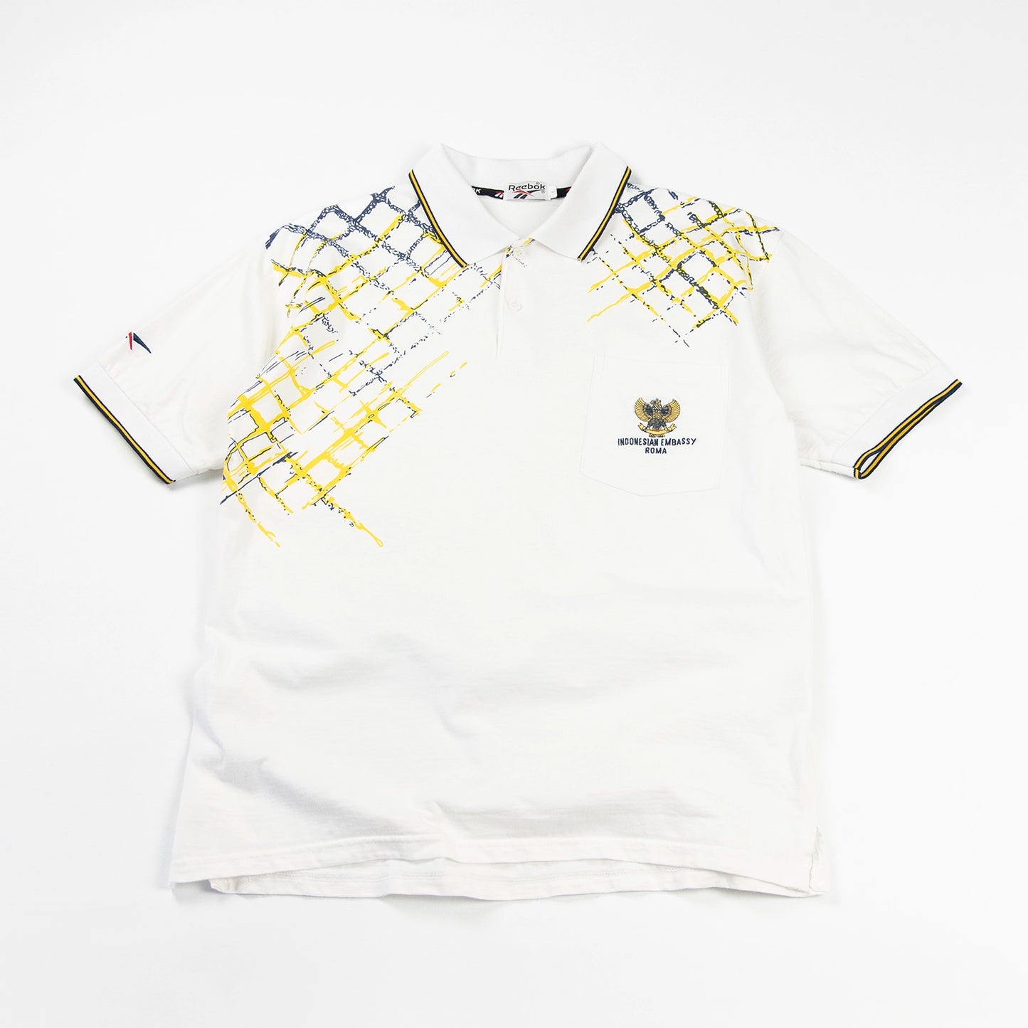 Polo vintage Reebok con grafica gialla e blu e logo Indonesian Embassy Roma sul petto
