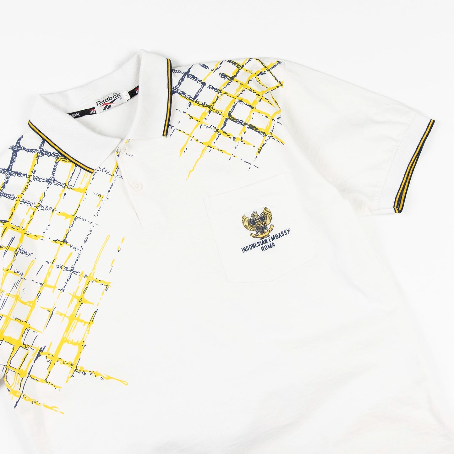 Polo vintage Reebok con grafica gialla e blu e logo Indonesian Embassy Roma sul petto